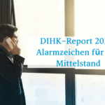 Mann steht mit einem Handy am Ohr am Fenster und telefoniert. Im Vordergrund Schrift: DIHK-Report 2025 Alarmzeichen für den Mittelstand