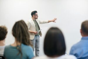 Mann hält Präsentation vor einer größeren Gruppe ab.