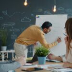Mann präsentiert Ideen auf Whiteboard für Kollegen
